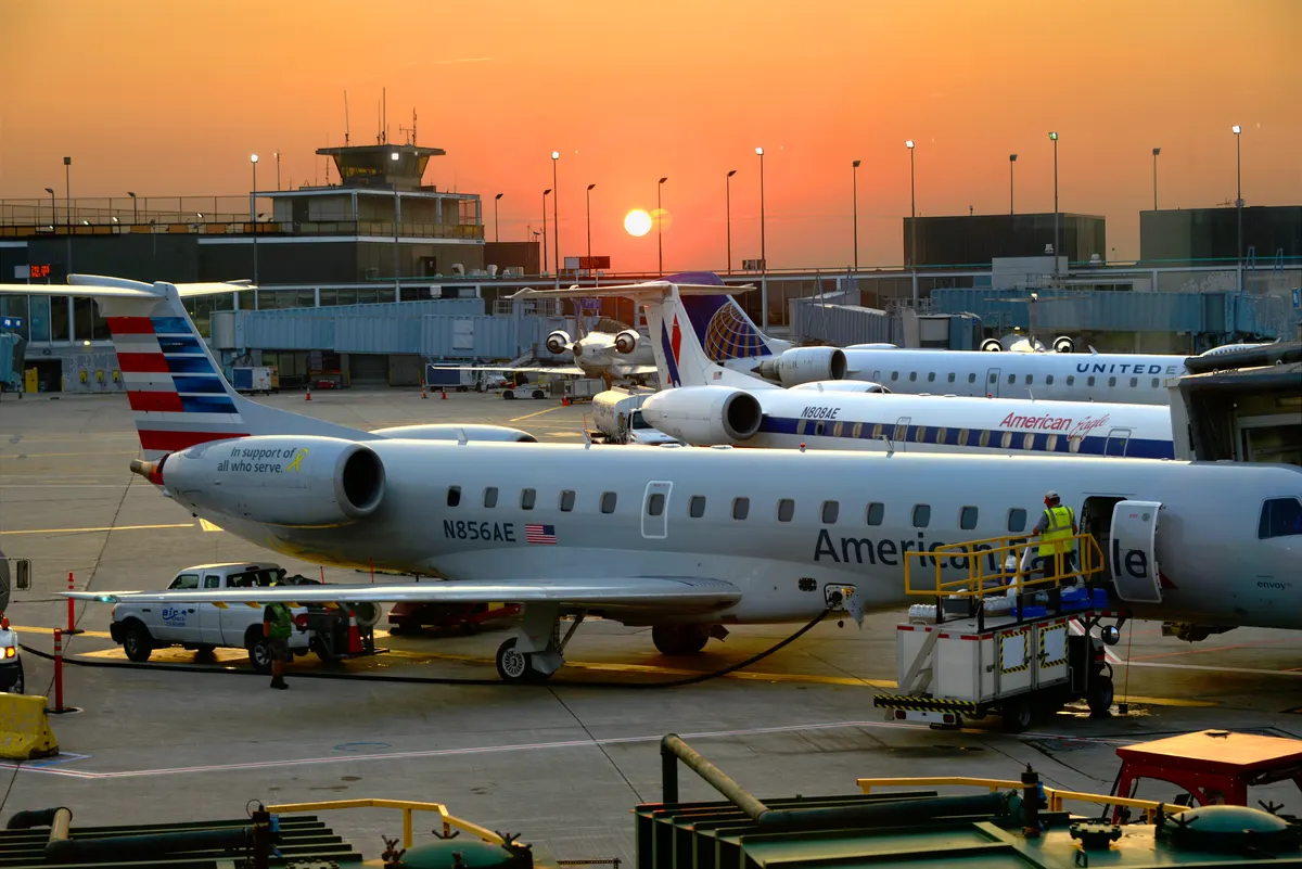 Airliners on the apron at Chicago O’Hare under an orange sunset, with the control tower on the horizon.